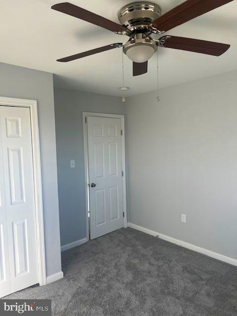 unfurnished bedroom featuring dark colored carpet and ceiling fan