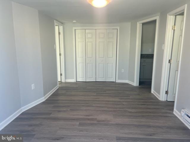 unfurnished bedroom featuring a closet and dark wood-type flooring