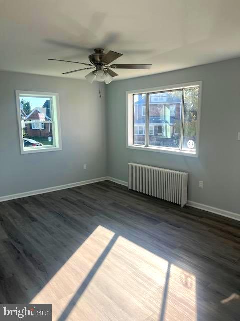 spare room with ceiling fan, radiator heating unit, and dark hardwood / wood-style floors