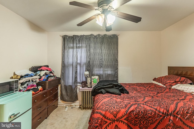 bedroom with refrigerator, light carpet, radiator heating unit, and ceiling fan