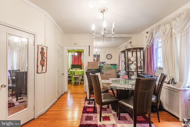 dining space featuring ornamental molding, a notable chandelier, radiator heating unit, and light wood-type flooring