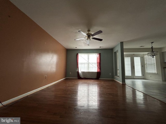 unfurnished room featuring ceiling fan with notable chandelier and dark hardwood / wood-style flooring