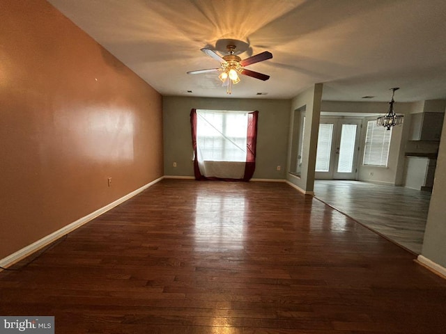 unfurnished room featuring ceiling fan with notable chandelier and dark hardwood / wood-style floors