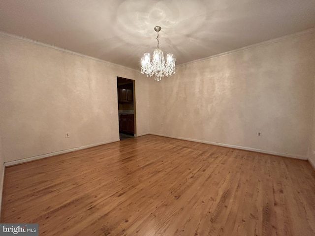 spare room with light hardwood / wood-style flooring, a chandelier, and crown molding