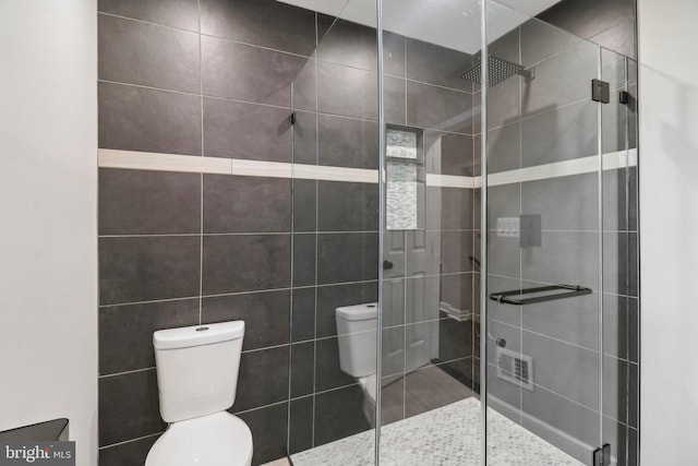 bathroom featuring tile walls, walk in shower, and toilet