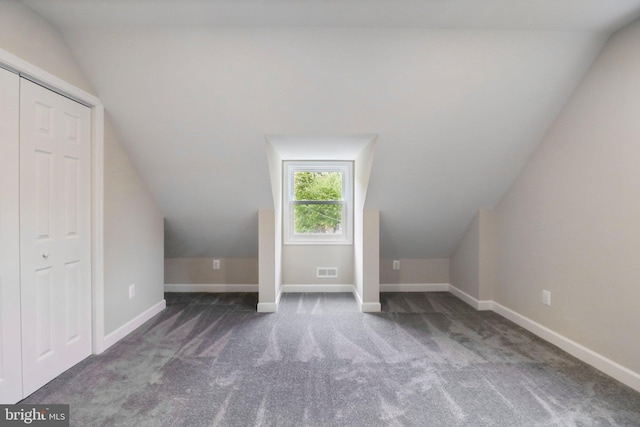 bonus room with lofted ceiling and dark colored carpet