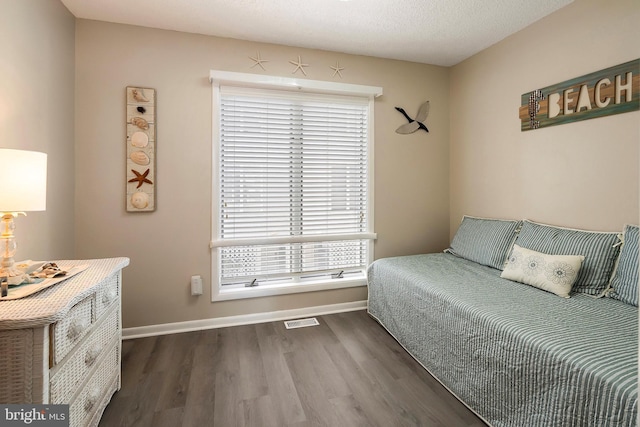 bedroom with wood finished floors, baseboards, and visible vents