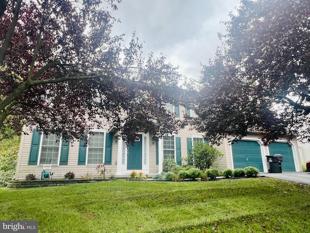 view of property hidden behind natural elements featuring a garage and a front lawn