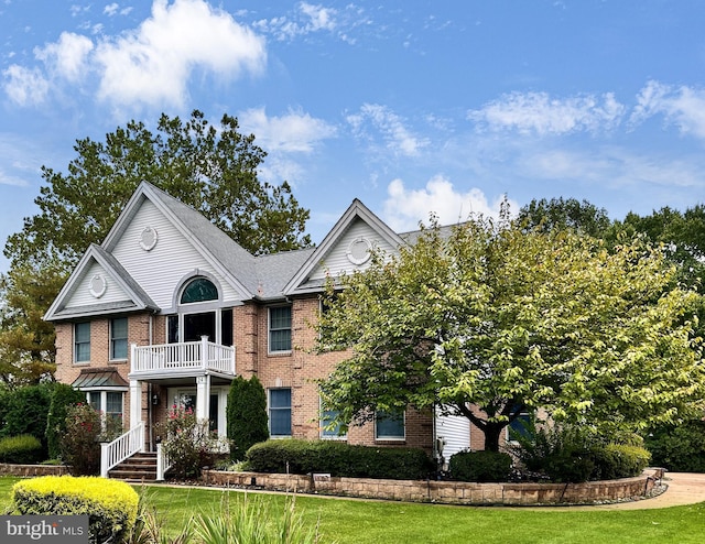 view of front of property featuring a balcony and a front yard