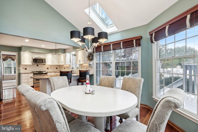 dining area featuring a skylight, hardwood / wood-style floors, an inviting chandelier, and high vaulted ceiling