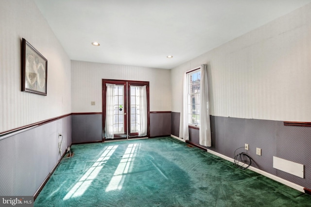 spare room featuring french doors and dark colored carpet