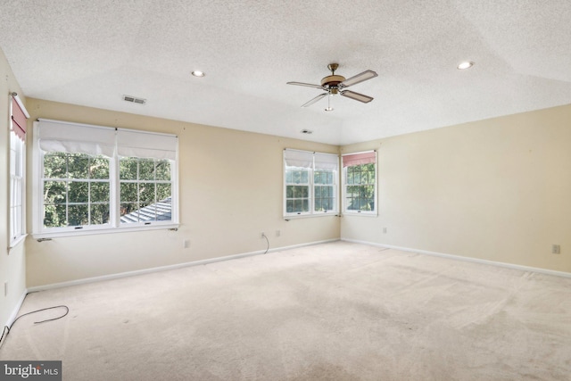 empty room with ceiling fan, light colored carpet, a textured ceiling, and a healthy amount of sunlight