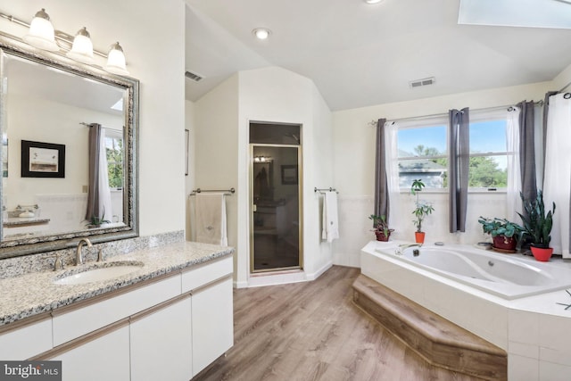 bathroom featuring hardwood / wood-style floors, vanity, shower with separate bathtub, and lofted ceiling with skylight