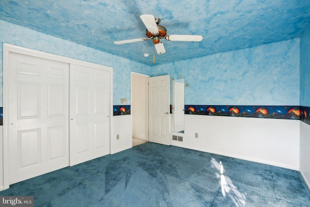 unfurnished bedroom featuring ceiling fan, a closet, and dark carpet