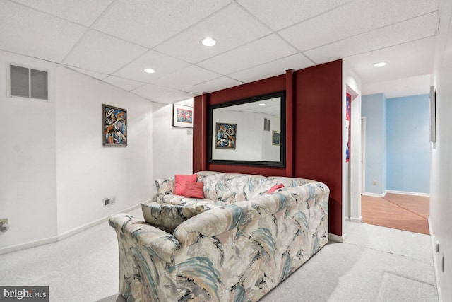 living room featuring a drop ceiling and light colored carpet