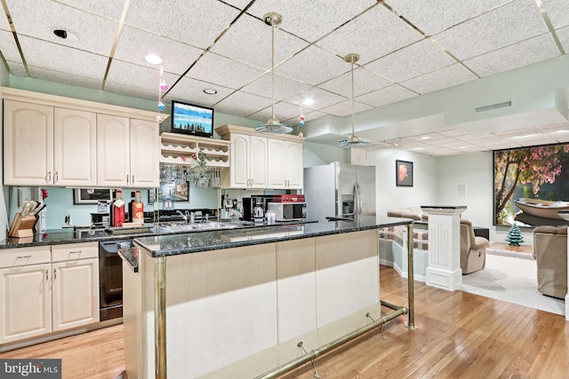 kitchen featuring a kitchen island, dark stone countertops, light hardwood / wood-style floors, appliances with stainless steel finishes, and decorative light fixtures