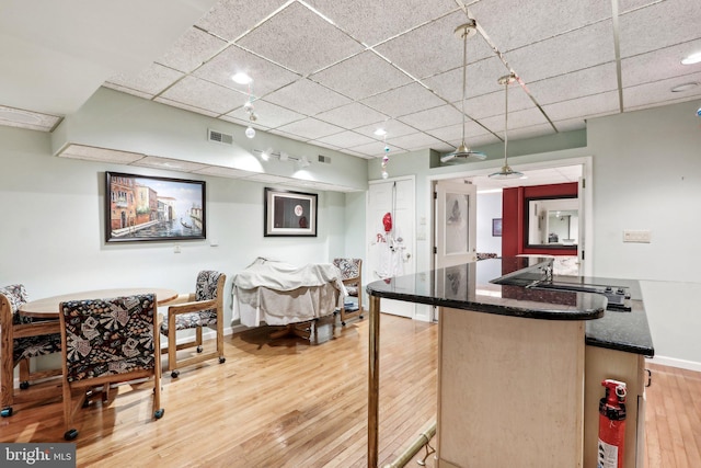 kitchen with a paneled ceiling, a breakfast bar, and light hardwood / wood-style flooring