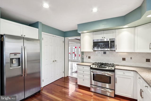 kitchen featuring dark hardwood / wood-style floors, appliances with stainless steel finishes, backsplash, and white cabinetry