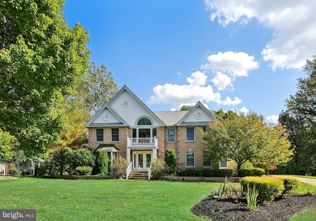 view of front of property featuring a balcony and a front lawn