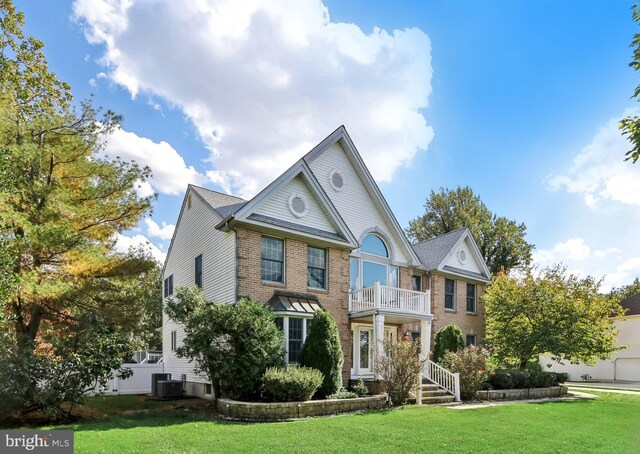 view of front facade with a front lawn, central AC unit, and a balcony