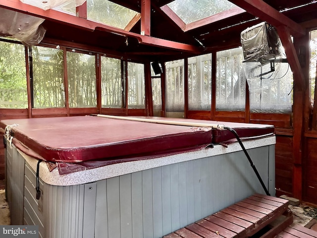 unfurnished sunroom with a hot tub and vaulted ceiling with skylight