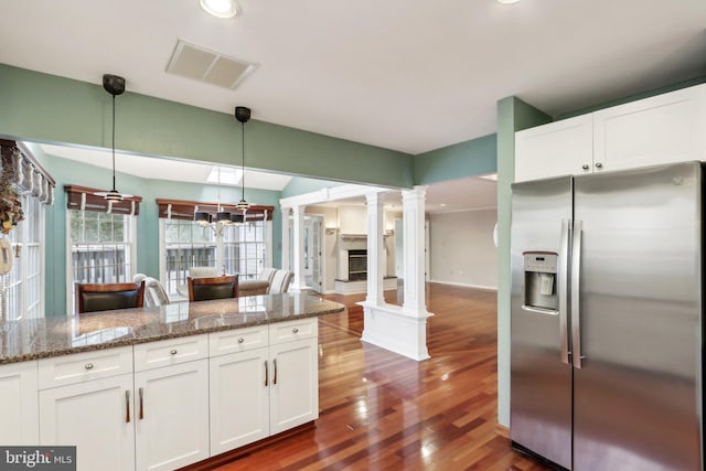 kitchen with white cabinets, stainless steel fridge, dark hardwood / wood-style flooring, ornate columns, and decorative light fixtures