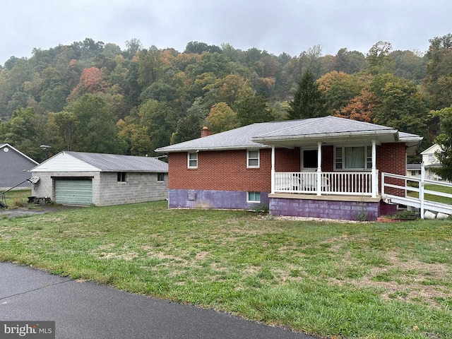 view of front of home featuring a porch, an outbuilding, a front lawn, and a garage