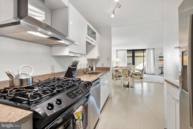 kitchen with light stone counters, range hood, white cabinets, and stainless steel appliances