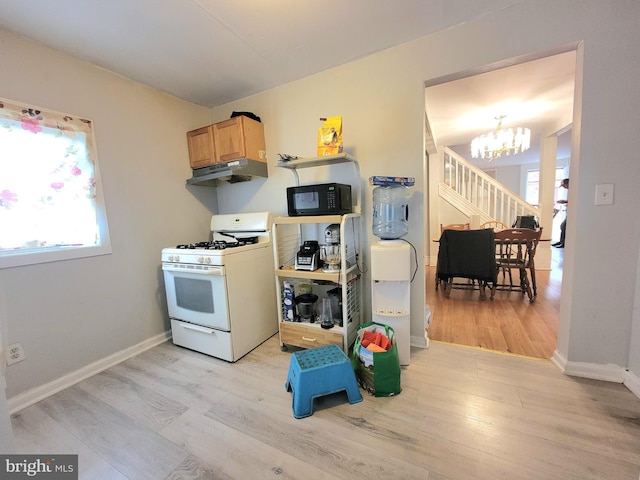 kitchen with white range with gas stovetop, a notable chandelier, and light hardwood / wood-style floors