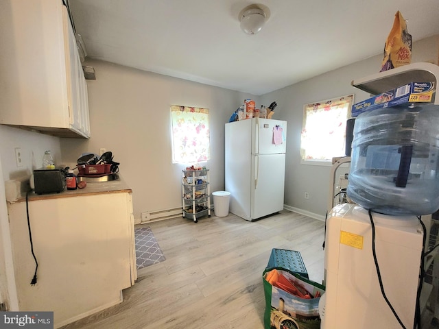 kitchen with white fridge, white cabinetry, light hardwood / wood-style flooring, and a baseboard heating unit