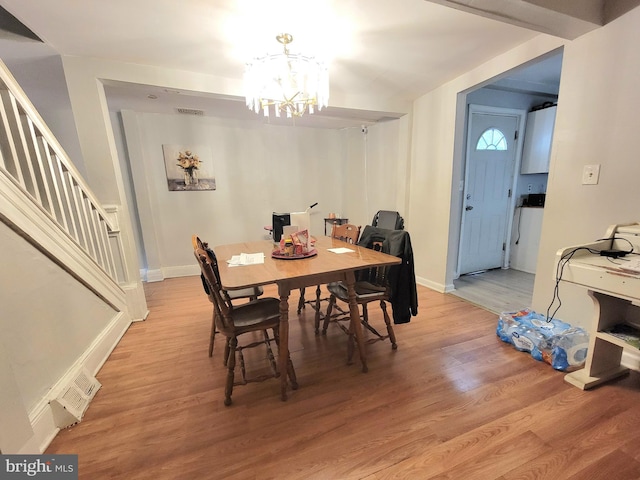 dining space featuring hardwood / wood-style flooring and an inviting chandelier