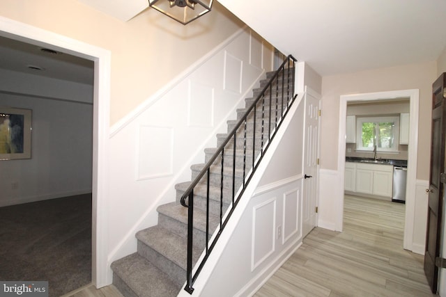 stairway featuring wood-type flooring and sink