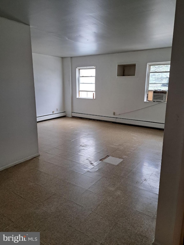 unfurnished room with cooling unit, a baseboard heating unit, and plenty of natural light