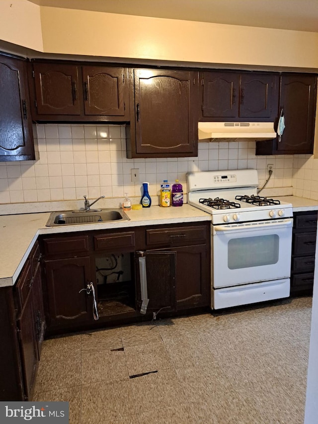 kitchen with dark brown cabinets, white gas range, tasteful backsplash, and sink