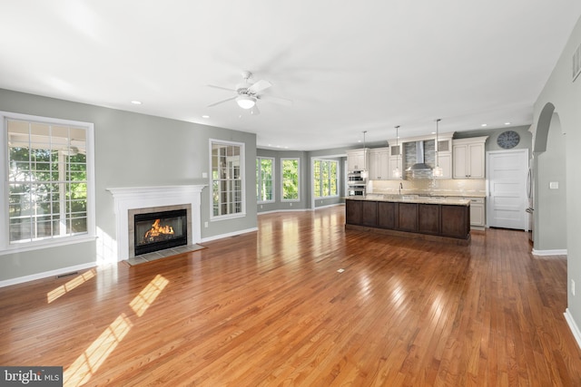 unfurnished living room with ceiling fan, wood-type flooring, and sink