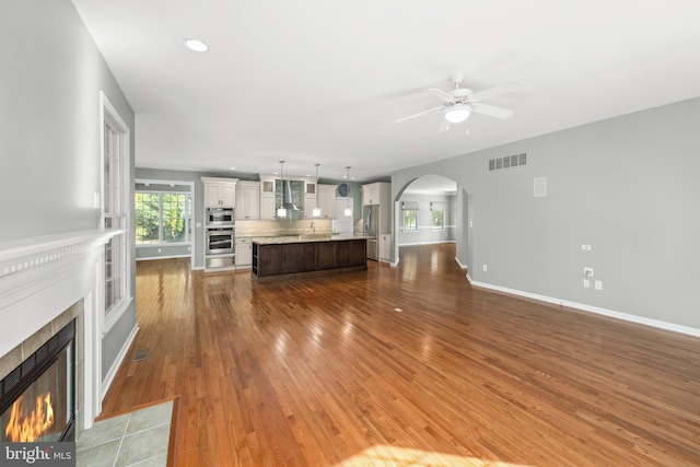 unfurnished living room with ceiling fan, wood-type flooring, and a fireplace