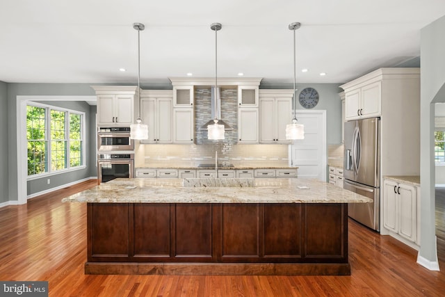 kitchen with dark wood-type flooring, white cabinets, decorative light fixtures, a large island, and stainless steel appliances