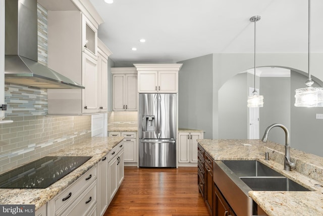 kitchen with stainless steel fridge with ice dispenser, white cabinetry, and wall chimney range hood