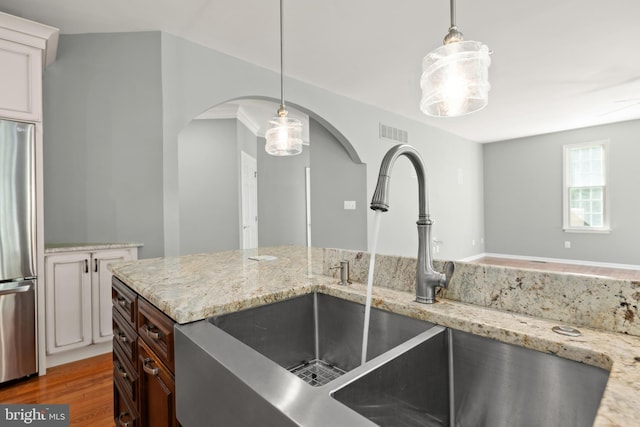 kitchen featuring pendant lighting, hardwood / wood-style floors, sink, dark brown cabinets, and stainless steel refrigerator