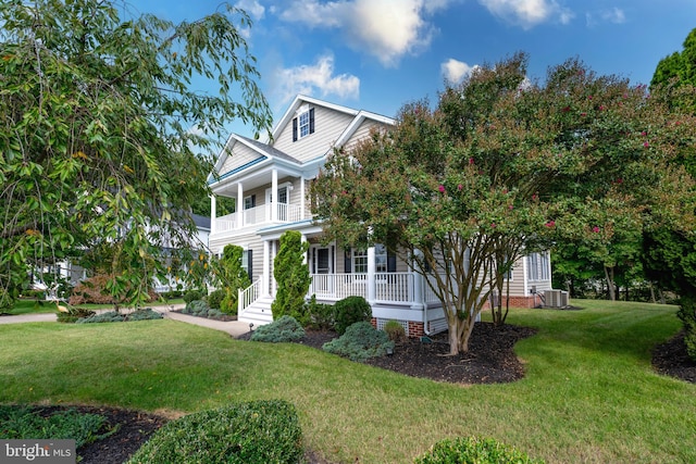 view of front of home featuring a porch, a balcony, a front lawn, and central AC unit