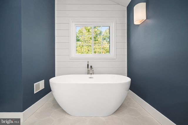 bathroom featuring lofted ceiling, tile patterned floors, and a bathing tub