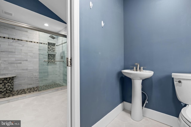 bathroom featuring tile patterned floors, vaulted ceiling, toilet, and a shower with shower door