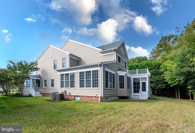 rear view of house with a sunroom, a lawn, and central AC