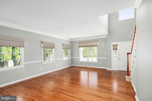 unfurnished living room featuring hardwood / wood-style flooring, ornamental molding, and a wealth of natural light