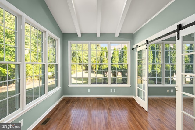 unfurnished sunroom featuring vaulted ceiling with beams, a wealth of natural light, and a barn door