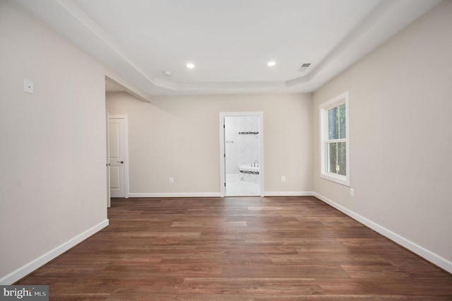 unfurnished room featuring dark hardwood / wood-style floors and a tray ceiling