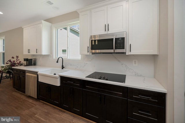 kitchen with sink, stainless steel appliances, light stone counters, dark hardwood / wood-style flooring, and white cabinets