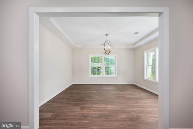 unfurnished room with a notable chandelier, dark hardwood / wood-style flooring, and a tray ceiling