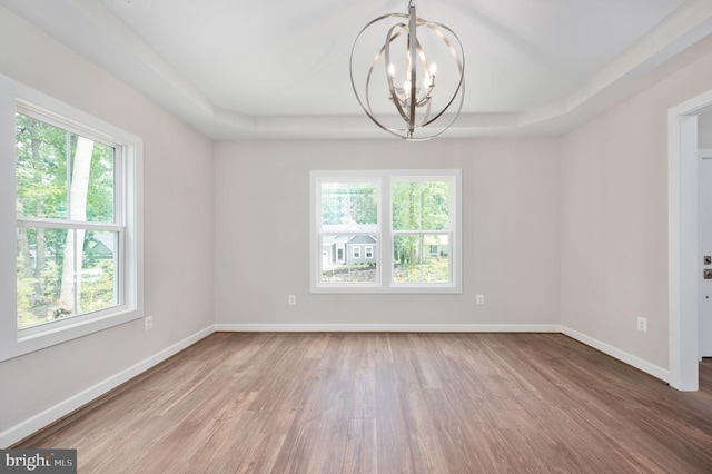 empty room featuring plenty of natural light, a tray ceiling, and a chandelier