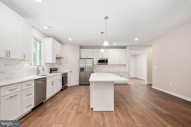 kitchen featuring white cabinets, sink, hanging light fixtures, a kitchen island, and stainless steel appliances